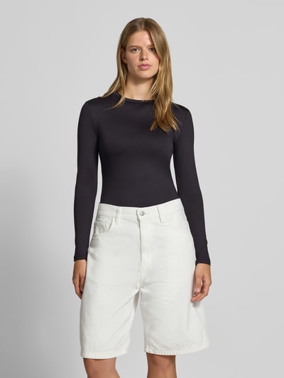 Vrouwenmodel draagt zwart shirt met lange mouwen met ronde hals, Slim Fit Langarmshirt mit Rundhals-Ausschnitt model 'LULA' van PIECES, witte broek, Ganzkörperaanzicht van voren, Dames shirt met lange mouwen van PIECES.