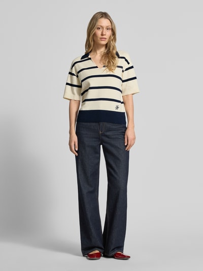 Modelka nosi Regular Fit Pullover aus reiner Baumwolle von Tommy Hilfiger, efekt: wzór na całej powierzchni, wzór w paski, wyhaftowane logo, kołnierzyk polo, dekolt w serek, krótki rękaw, prążkowane zakończenia, drobny splot, bawełna; pełny widok od przodu.