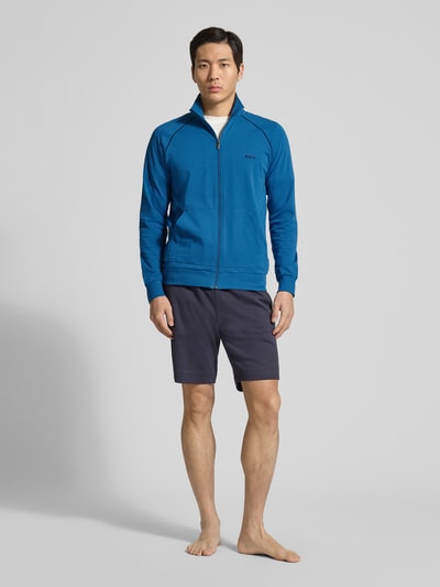 Männermodel trägt Regular Fit Sweatjacke aus Baumwoll-Mix Modell 'Mix&Match' von BOSS in Blau mit Reißverschluss und Kontraststreifen, unifarben, Stehkragen, Label Stitching, Sweat-Material, seitliche Taschen, Ganzkörperansicht von vorne.