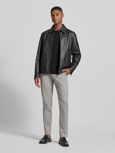 Męski model nosi Chino mit Eingrifftaschen von Lindbergh z bawełny z domieszką elastanu, krój slim fit, jasnoszary, szerokość w rozmiarze 32/32: 40 cm, długość nogawki od wewnątrz: 79 cm, widok całej sylwetki z przodu.