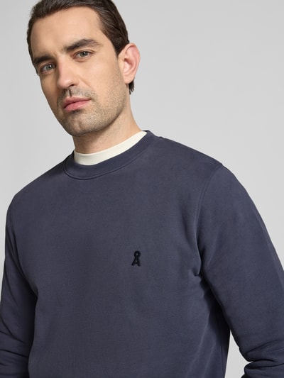 Männermodel trägt Regular Fit Sweatshirt aus reine bio katoen Modell 'BAARO FLEECE' van Armedangels, effen donkerblauw, logo-detail, ronde hals, lang mouw, geribde boorden, Nahaufnahme Oberkörper.