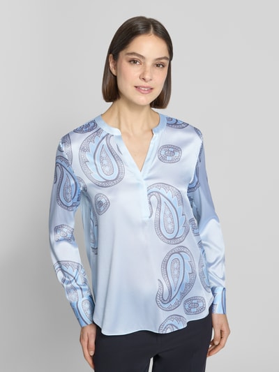 Frauenmodel trägt Regular Fit Bluse aus Seiden-Mix von HERZENS mit Tunika-Ausschnitt, Allover-Paisley-Print, langärmelig, Hellblau, Ganzkörperansicht von vorne. Rückenlänge bei Größe 36: 68 cm, Ärmellänge: 62 cm, Elastischer Seiden-Mix.