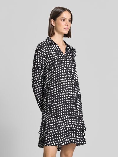 Frauenmodel trägt Knielanges Kleid aus reiner Viskose von Emily Van den Bergh in Schwarz mit weißen Punkten, entspannter Schnitt, Umlegekragen, langärmlig, Damen Kleid, Nahaufnahme Oberkörper.