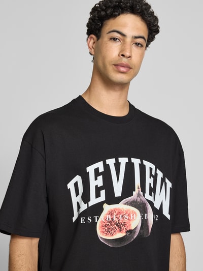 Männermodel trägt Relaxed Fit T-Shirt mit Logo-Print von REVIEW aus reiner Baumwolle, Halbarm, Rundhalsausschnitt, Nahaufnahme Oberkörper.