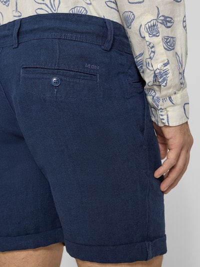 Mężczyznamodel nosi granatowe 'Leinenshorts mit Bindegürtel und Gesäßtaschen' od MCNEAL z lnu, z tyłu kieszeń z wypustką, wyhaftowane logo, szerokość w rozmiarze M: 45 cm, długość wewnętrzna nogawki: 16 cm, krój straight fit, zapięcie na guzik i zamek błyskawiczny, wiązany pasek, wpuszczane kieszenie, zakładka na dole, widok z tyłu, zbliżenie części tylnej