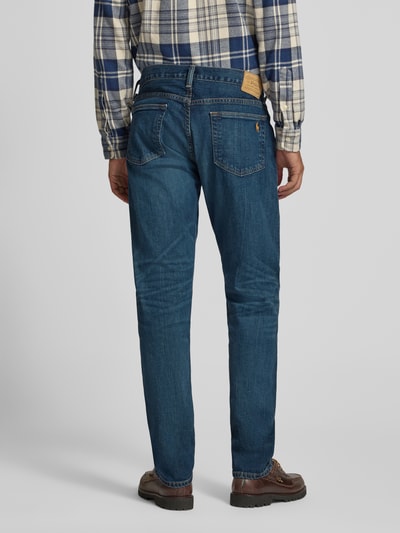 Männermodel trägt Slim Fit Jeans mit Used Waschung von POLO RALPH LAUREN, Denim in Medium Wash, 5-Pocket-Design, Ganzkörperansicht Rückansicht.