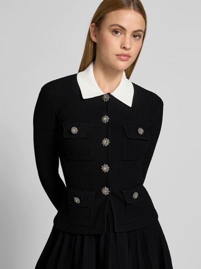 Frauenmodel trägt Minikleid aus Viskose-Mix von Self-Portrait in Schwarz mit weißen Kragen, Ziersteinbesatz, Strick-Optik, Nahaufnahme Oberkörper.
