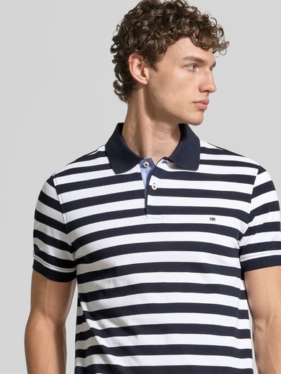 Männermodel trägt Modern Fit Poloshirt mit Logo-Stitching von Christian Berg Men in Marine-Weiß, Reine Baumwolle, Polokragen, kurze Knopfleiste, Nahaufnahme Oberkörper.