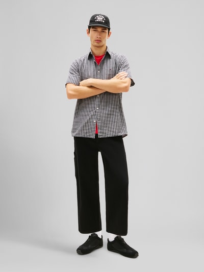 Männermodel trägt Regular Fit Freizeithemd aus Baumwoll-Mix von Tommy Jeans mit Optik:Allover-Muster, gestreift, Logo-Stitching, Ganzkörperansicht von vorne
