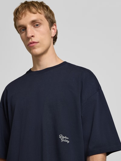 Männermodel trägt T-Shirt mit Stitching und Rundhalsausschnitt von REVIEW aus reiner Baumwolle, oversized, dunkelblau, Nahaufnahme Oberkörper.