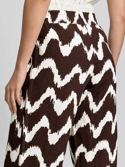 Männermodel trägt Wide Leg Pants aus Viskose-Mix mit elastischem Bund von OPUS PANTS, brązowo-białe wzory, mieszanka wiskozy i lnu, krój loose fit, elastyczny pas, model 'Malotta', szerokość w rozmiarze 36: 37 cm, długość wewnętrzna nogawki w rozmiarze 36: 79 cm, detailaufnahme