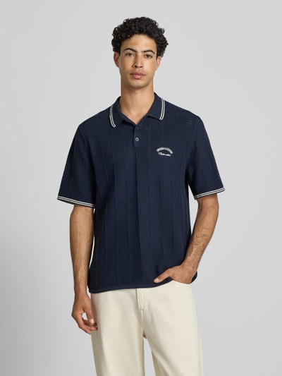 Männermodel draagt heren poloshirt van puur katoen, regular fit, model 'Menton' van Jack & Jones in tricotlook, donkerblauw, korte mouw, ruglengte maat M 70 cm, nahaufnahme oberkörper.