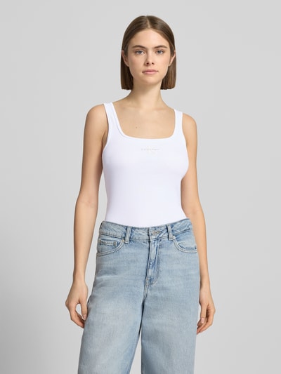 Kobiece modelka nosi Slim Fit Top mit Logo-Print Modell 'Scoop' od Calvin Klein Jeans, biały kolor, krój slim fit, dekolt okrągły, długość pleców w rozmiarze S: 42 cm, na tle szarym, widok całej sylwetki z przodu.