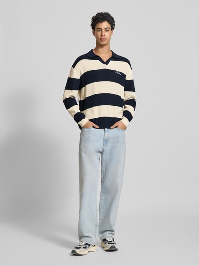 Männermodel trägt Regular Fit Strick-Poloshirt mit Block-Streifen von REVIEW aus reiner Baumwolle, Logo-Bestickung, Ganzkörperansicht von vorne.