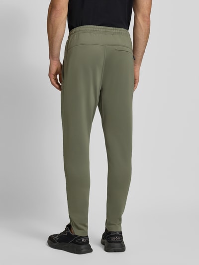 Männermodel draagt Regular Fit Sweatpants uit sneldrogend materiaal Model 'HICON ACTIVE' van BOSS Green, look: effen, achterzak, boord elastisch, zij-steekzakken, labelprintdetails, flatlock-naden, kleur olijfgroen, Ganzkörperansicht Rückansicht.
