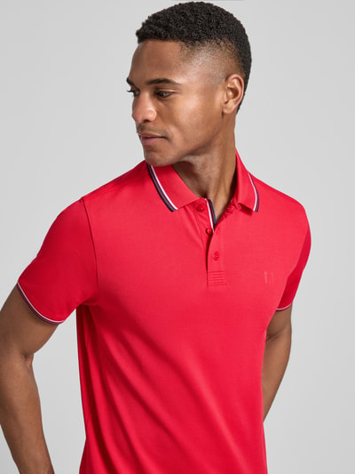 Męski model nosi Modern Fit Poloshirt mit Logo-Print Modell 'Keep Dry' od RAGMAN, bawełniany miks, kołnierzyk polo, krótka lista guzików, czerwony kolor, widoczne logo, tekstura gładka, widok na górną część ciała z przodu.