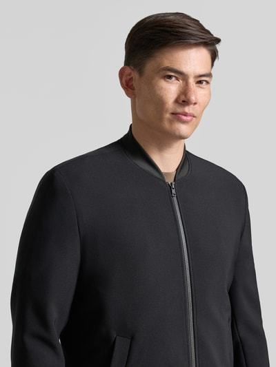 Männermodel trägt Blouson mit seitlichen Eingrifftaschen von MCNEAL, schwarz, Stehkragen, Reißverschluss, Nahaufnahme Oberkörper. Regular Fit, Material-Mix mit Stretch-Anteil, elastische Abschlüsse.