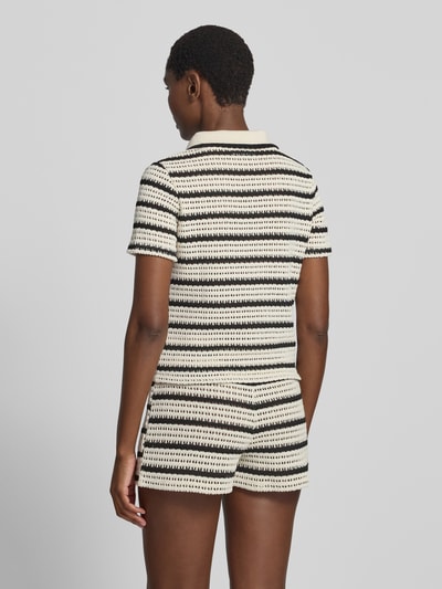 Frauenmodel trägt Strickshirt mit Polokragen Modell 'MIFFY' von MANGO, creme-schwarz gestreift, feine Stricktextur, Rückenansicht, Ganzkörperansicht Rückansicht, Material-Mix mit Baumwoll-Anteil, Slim Fit, kurze Ärmel.