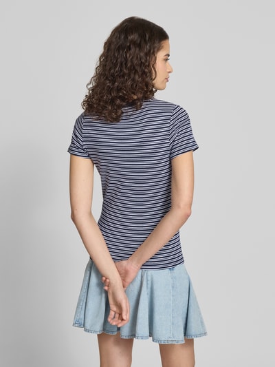 Kobiece modelka nosi Slim Fit T-Shirt aus reiner Baumwolle od Levi's®, wzór w paski, łatka z logo, okrągły dekolt, krótkie rękawy, jasnoniebieska spódnica, kolorystyka granatowo-biała, tekstura bawełniana tkanina, widok całej sylwetki od tyłu.