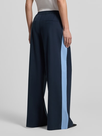 Frauenmodel trägt Fließende Viskose-Hose mit Kontraststreifen - curated by Tinvcb von SIC, weites Bein, elastischer Bund, Rückansicht.