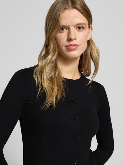 Frauenmodel trägt Slim Fit Strickjacke aus Viskose-Mix Modell 'NORA' von Pieces, unifarben schwarz, Crew Neck, Nahaufnahme Oberkörper.