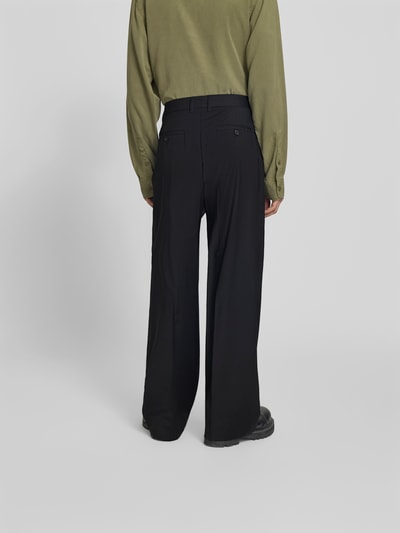 Männermodel trägt Wide Fit Stoffhose aus Woll-Mix von Filippa K in Schwarz mit Bügelfalten und Gesäßtaschen, Ganzkörperansicht Rückansicht.