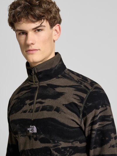 Männermodel trägt Fleecepullover mit Troyer-Kragen von The North Face in Schwarz und Braun, lockere Passform, Nahaufnahme Oberkörper.