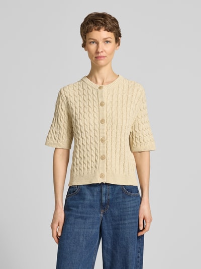 Kobieta nosi kardigan z mieszanki bawełny i lnu model 'Diva' od My Essential Wardrobe, krój regular fit, kremowy, ścieg warkoczowy, okrągły dekolt, listwa guzikowa, rękaw o dł. 1/2, długość tyłu w rozmiarze S: 50 cm, długość rękawów w rozmiarze S: 28 cm, zdjęcie całej sylwetki z przodu.