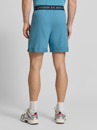 Männermodel draagt Shorts met elastische band en logo van Under Armour in regular fit met steekzakken, blauw, Ganzkörperansicht Rückansicht. Heren korte broek, bandwijdte maat M 39 cm, binnenbeenlengte maat M 15 cm.
