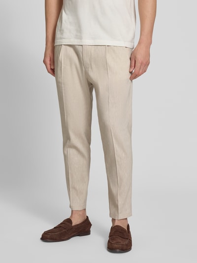 Męski model nosi Hose mit Bügelfalte und elastischem Bund Modell 'CHASY' od Drykorn z lnianej mieszanki z wiskozą, krój slim fit, beżowy kolor, francuskie kieszenie, tylne kieszenie, szerokość w rozmiarze 32/32: 44 cm, długość nogawki wewnętrznej: 66 cm, widok całej sylwetki z przodu.