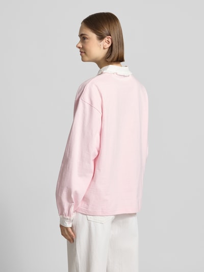 Frauenmodel trägt Oversized Poloshirt mit Kontrastbesatz Modell 'Jolina' von OH APRIL aus reiner Baumwolle, Langärmlig, Rückenlänge 65 cm, Ganzkörperansicht Rückansicht.