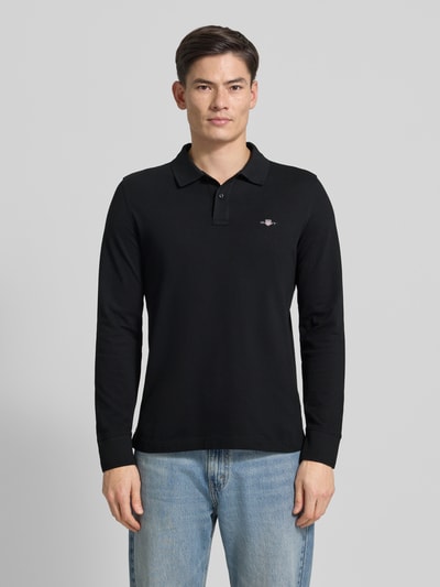 Męski model nosi Regular Fit Poloshirt mit Label-Stitching od Gant, czarna bawełna, prosty krój, widok całej sylwetki z przodu.