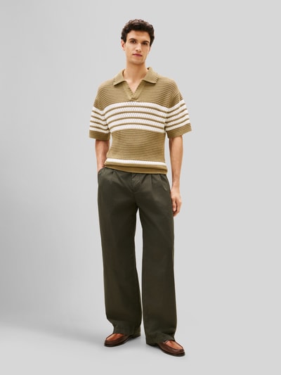 Männermodel trägt Loose Fit Hose mit Bundfalten von Tommy Hilfiger in Optik: Unifarben aus reine Baumwolle, Ganzkörperansicht von vorne.