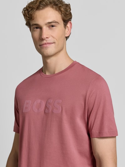Męski model trägt Regular Fit T-Shirt aus reiner Baumwolle Modell 'Te_Logo' von BOSS Orange w kolorze matowego różu, haftowane logo, gładka tekstura, Nahaufnahme Oberkörper.