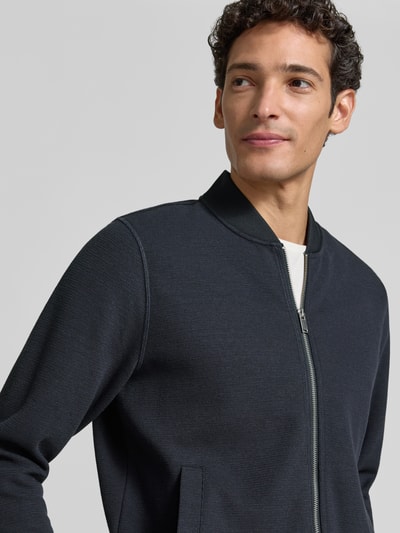 Männermodel trägt Sweatjacke mit Stehkragen von Christian Berg Men in Dunkelblau, glatte Textur, Nahaufnahme Oberkörper, Material-Mix mit Baumwoll-Anteil.