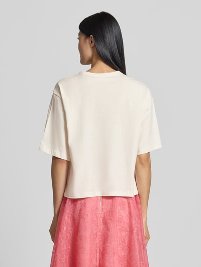 Frauenmodel trägt Regular Fit T-Shirt aus reiner Baumwolle von Jake*s Casual in Creme, kombiniert mit rosa Rock, Ganzkörperansicht Rückansicht.