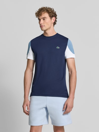 Männermodel trägt Regular Fit Sport-T-Shirt im Colorblock-Design von Lacoste in Dunkelblau und Hellblau, Nahaufnahme Oberkörper, Herren Sport-T-Shirt von Lacoste Sport.