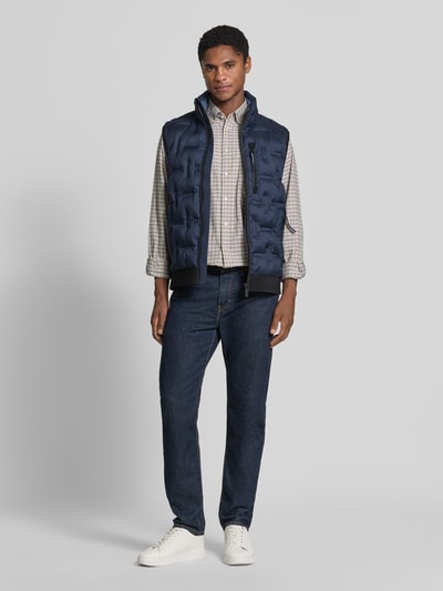Männermodel trägt Regular Fit Outdoor-Weste mit reflektierenden Elementen von Tom Tailor in Dunkelblau, Ganzkörperansicht von vorne. Herren Outdoor-Weste von Tom Tailor.