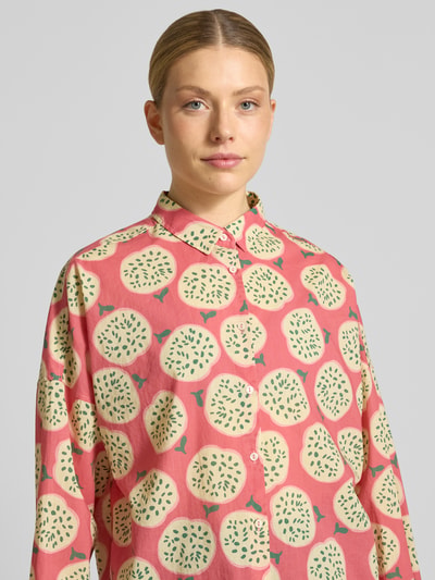 Frauenmodel trägt Relaxed Fit Bluse im Allover-Look Modell 'LUCY' von 0039 Italy aus Reine Baumwolle mit Hemdblusenkragen, Knopfleiste, rosa Grundton mit hellen runden Mustern, Nahaufnahme Oberkörper.