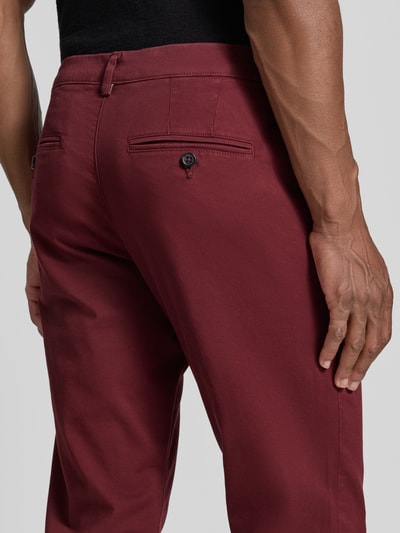 Männermodel trägt Slim Fit Chino aus Baumwoll-Mix Modell 'GABARDINE' von Selected in Dunkelrot, glatte Oberfläche, Nahaufnahme Rückansicht, Herren Chino.