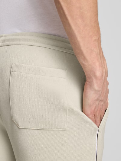 Männermodel trägt helle Hose mit sichtbarer Gesäßtasche aus strukturiertem Stoff, Nahaufnahme Hüfte.