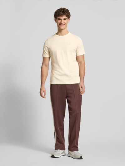 Männermodel trägt T-Shirt aus reiner Baumwolle von PUMA PERFORMANCE in Beige, gerader Schnitt, Rundhalsausschnitt, Ganzkörperansicht von vorne.