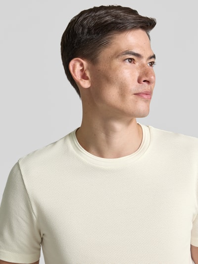 Männermodel trägt Regular Fit T-Shirt aus Baumwoll-Mix Modell 'TIBURT 240' von BOSS in Creme mit feiner Struktur, Nahaufnahme Oberkörper, Herren T-Shirt.