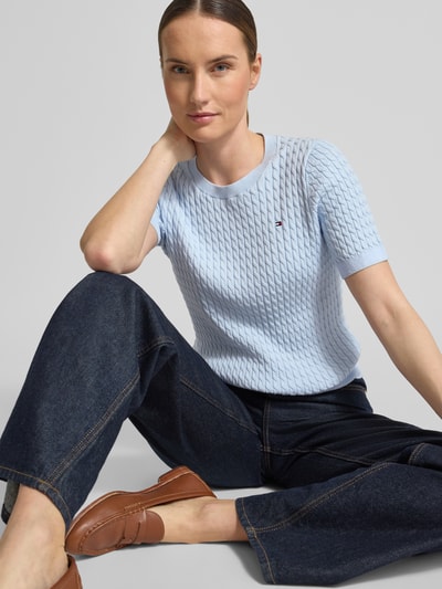 Vrouwenmodel draagt Slim Fit T-shirt uit zuiver katoen van Tommy Hilfiger, look: effen, kabelpatroon, logodetail, ronde hals, korte mouw, knitwear, lichtblauw; close-up bovenlichaam.