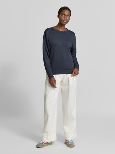 Frauenmodel trägt Relaxed Fit Sweatshirt mit elastischen Abschlüssen von MSCH Copenhagen, rundhals, dunkelblau, weiße Hose, Ganzkörperansicht von vorne.