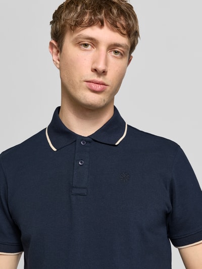 Männermodel trägt Regular Fit Poloshirt mit Logo-Stitching Modell 'Hedin' von Blend in Dunkelblau, reine Baumwolle, Nahaufnahme Oberkörper.