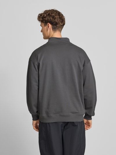 Männermodel trägt Relaxed Fit Sweatshirt mit Stehkragen und Reißverschluss von The North Face aus katoen in donkergrijs, label-stitching, relaxte fit, ruglengte 71 cm, mouwlengte 64 cm, Ganzkörperansicht Rückansicht.