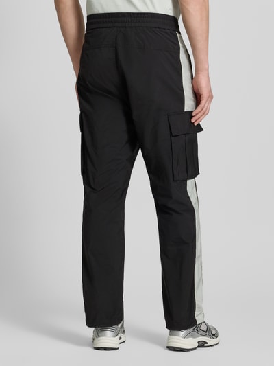 Männermodel trägt Regular Fit Cargohose mit Label-Applikation Modell 'COLAS262' von HUGO in Two-Tone-Optik aus Twill mit Cargotaschen, Ganzkörperansicht Rückansicht.