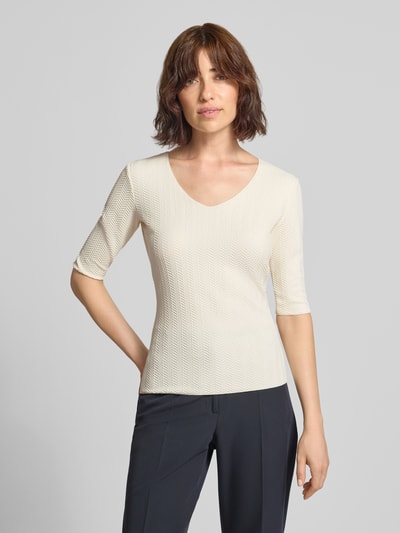 Frauenmodel trägt Regular Fit Bluse mit Strukturmuster von Emporio Armani in Creme mit V-Ausschnitt und Halbarm, Ganzkörperansicht von vorne.