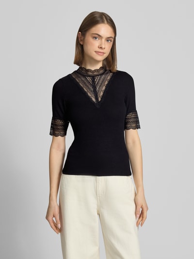 Vrouwenmodel draagt Slim Fit T-Shirt uit viscosemix model 'Tilde' van Only, effen zwart met kanten details, fijnrib, ronde hals, korte mouw, volledige vooraanzicht van het bovenlichaam.